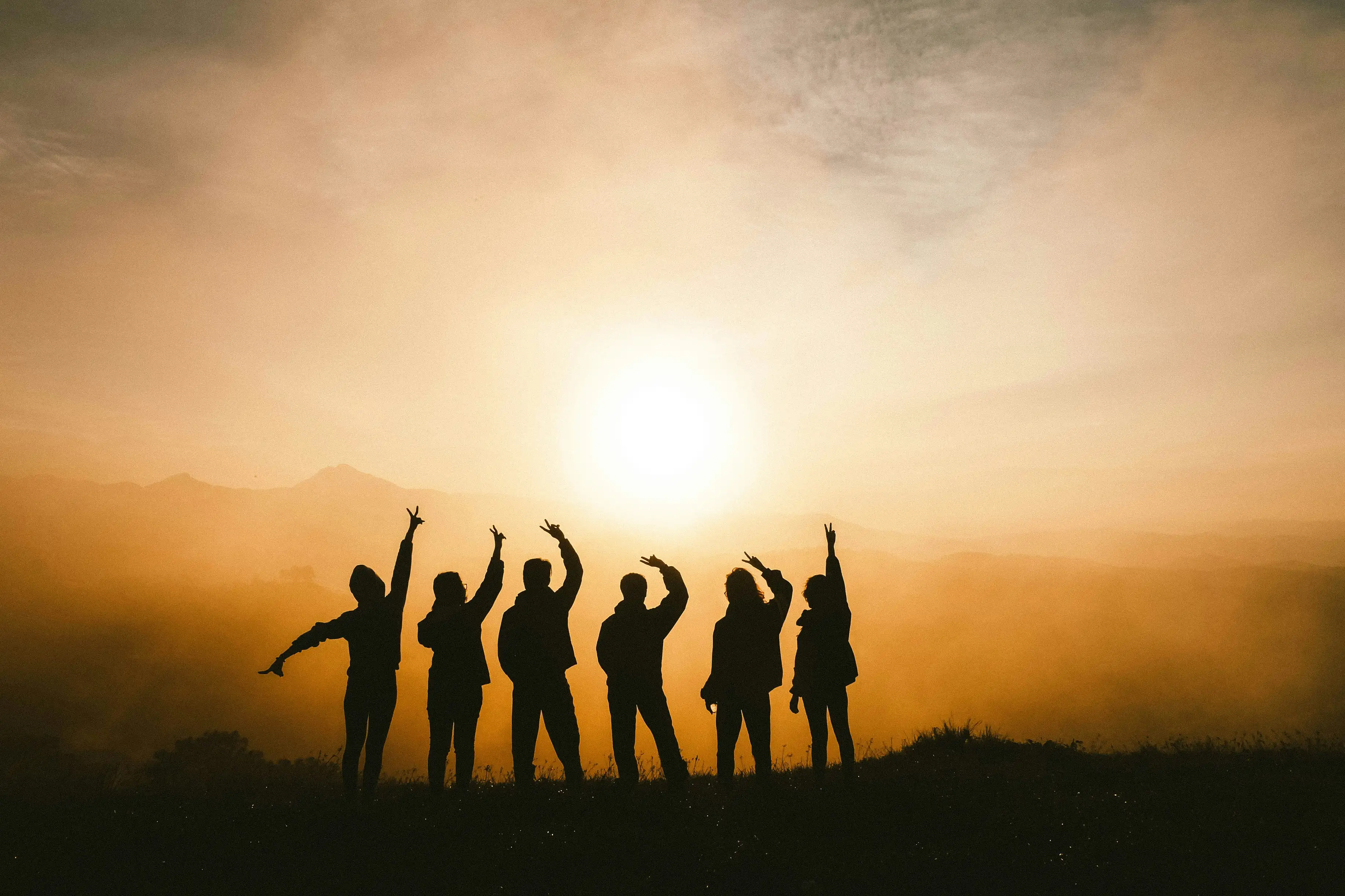 Group of friends enjoying sunset in the mountains