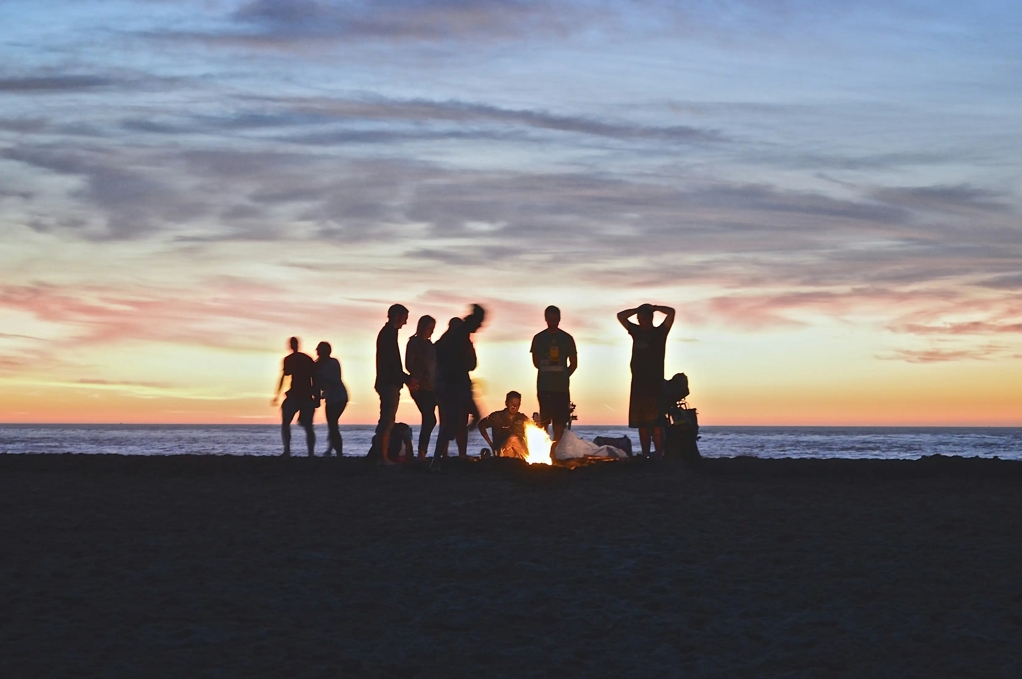 People enjoying a beach bonfire at sunset